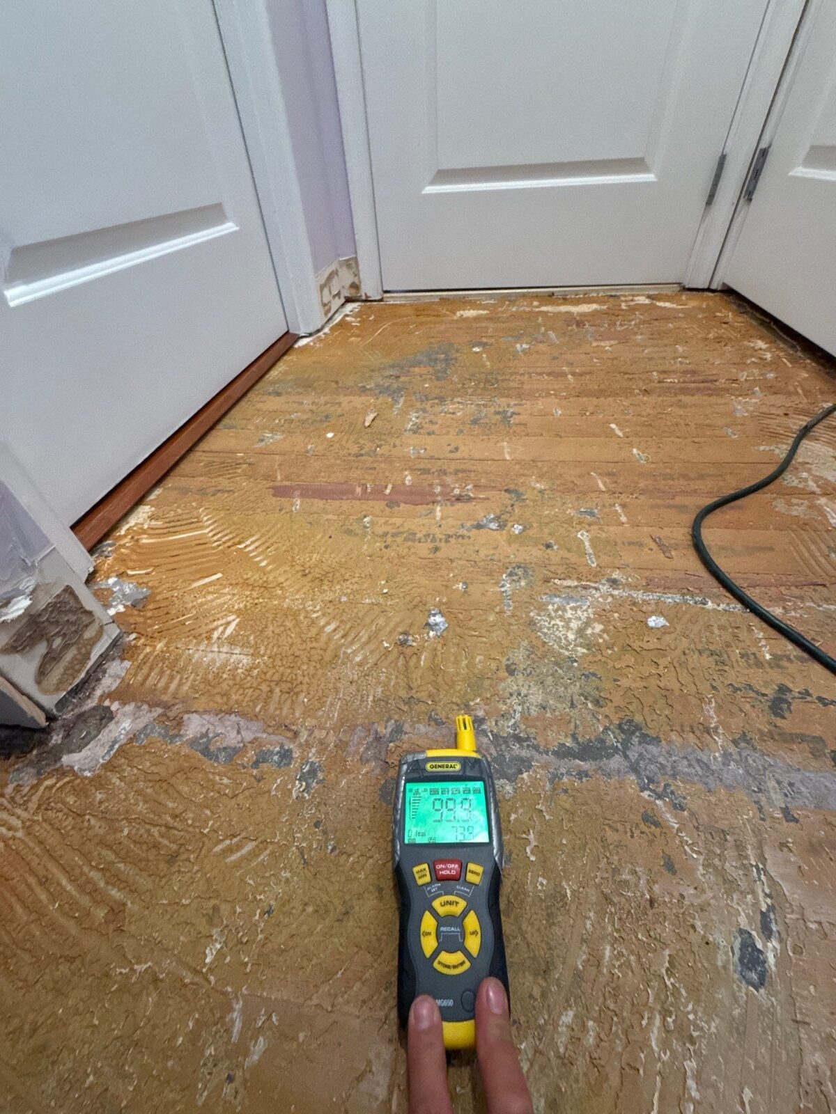 moisture meter on a saturated subfloor during water damage inspection, Arlington VA